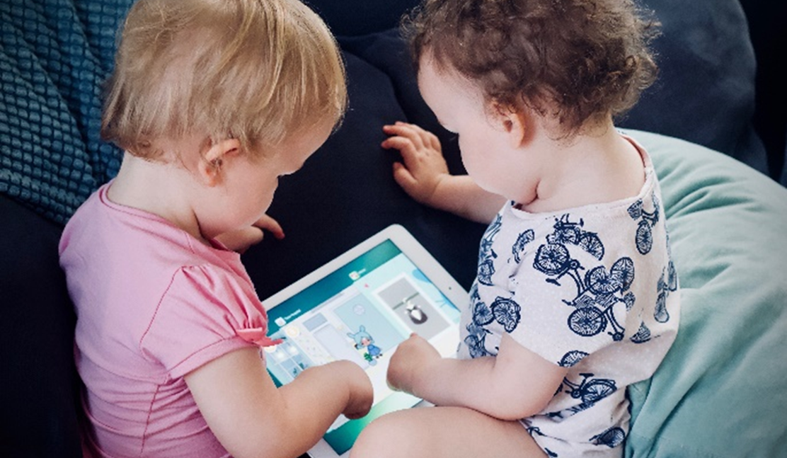 Två små barn tittar tillsammans på en läsplatta