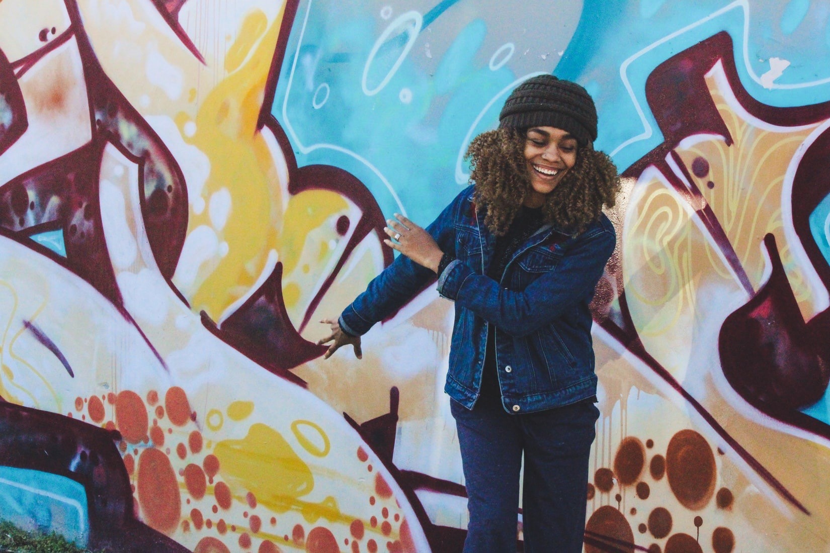 En ung kvinna framför en vägg med graffitti.