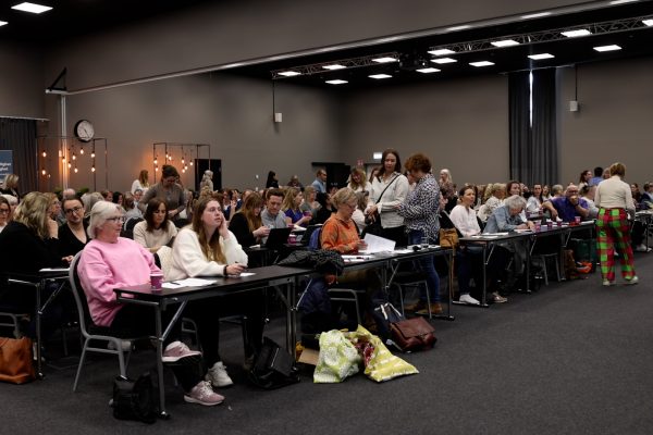 Stor konferenslokal med rader av sittande åhörare.