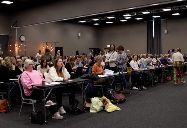 Stor konferenslokal med rader av sittande åhörare.