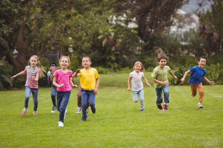 Springande och glada barn på en gräsmatta.