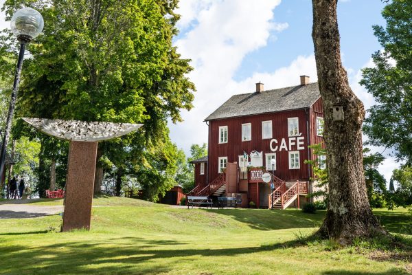 Ett äldre trähus i Dalsland med stor vit skylt som säger "Café". Huset är beläget i en grönskande park.