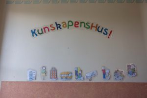 Klistermärken på en whiteboard med texten "Kunskapens hus". I nederkant klistermärken på olika figurer, bland annat kylskåp, hus, buss, sax etc.