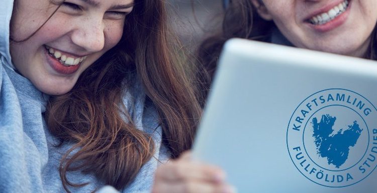 Två tjejer ler och tittar på en laptop-skärm.