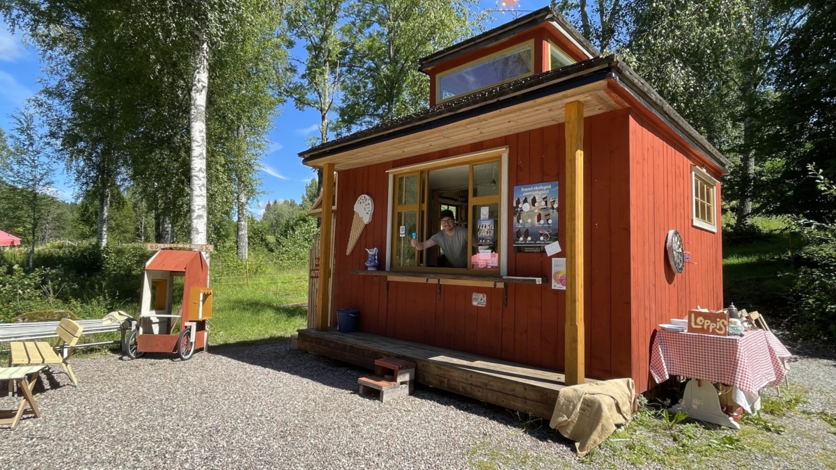 Röd liten kiosk där en man tittar ut från luckan.