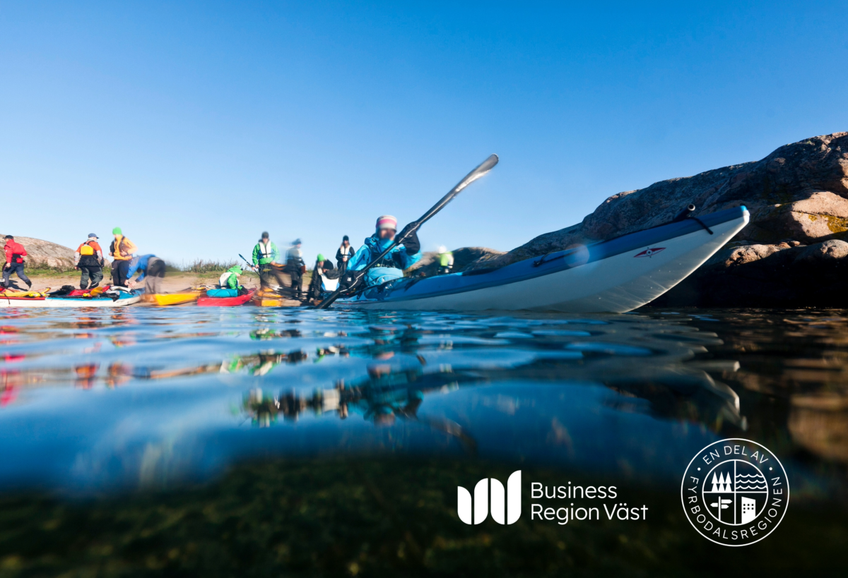 Flera personer paddlar kanot i färgglada kläder. Tagen från vattenytan.