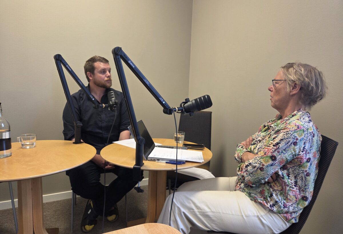 Poddinspelning med en man och en kvinna och två mikrofoner framför sig.