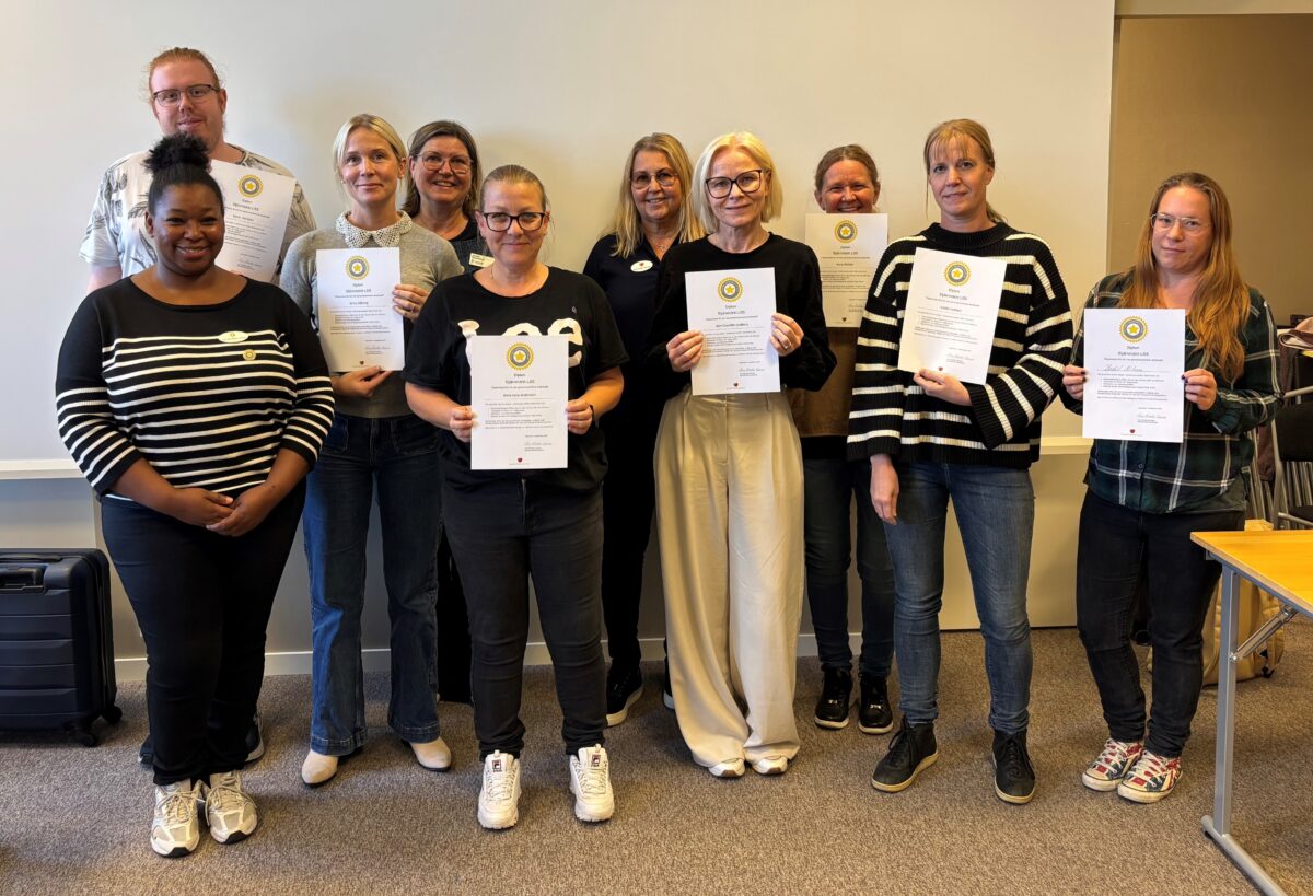 Gruppbild på tio personer där vissa av dem håller upp ett diplomliknande papper.