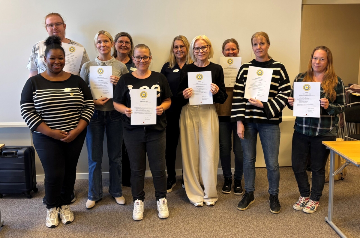 Gruppbild på tio personer där vissa av dem håller upp ett diplomliknande papper.