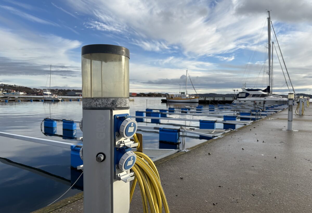 Laddningsstation för elbåtar. En kaj i bakgrunden med några segelbåtar.