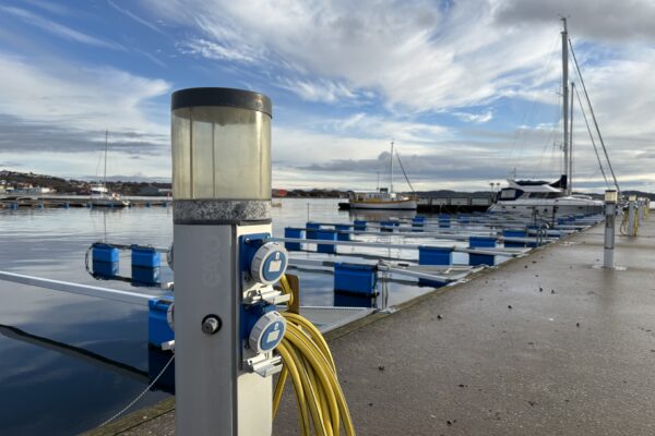 Laddningsstation för elbåtar. En kaj i bakgrunden med några segelbåtar.
