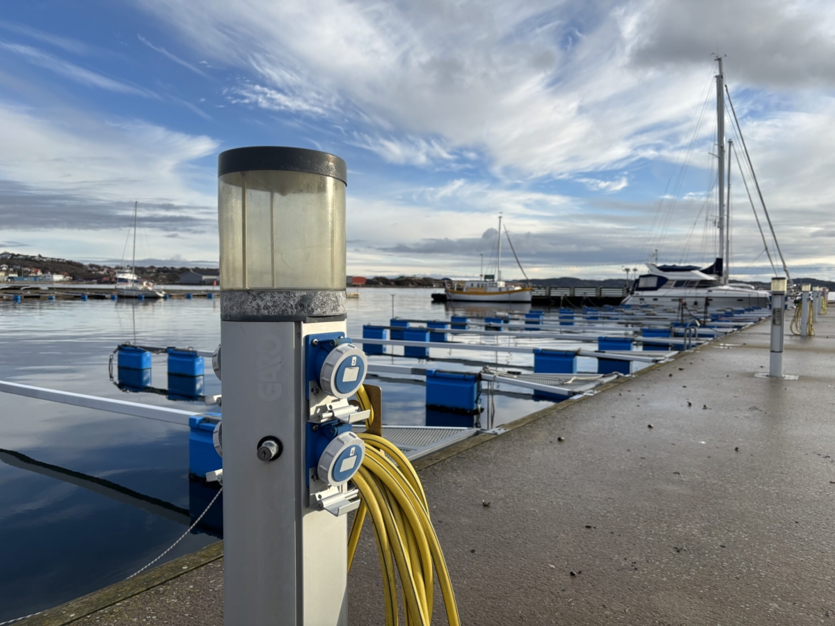 Laddningsstation för elbåtar. En kaj i bakgrunden med några segelbåtar.