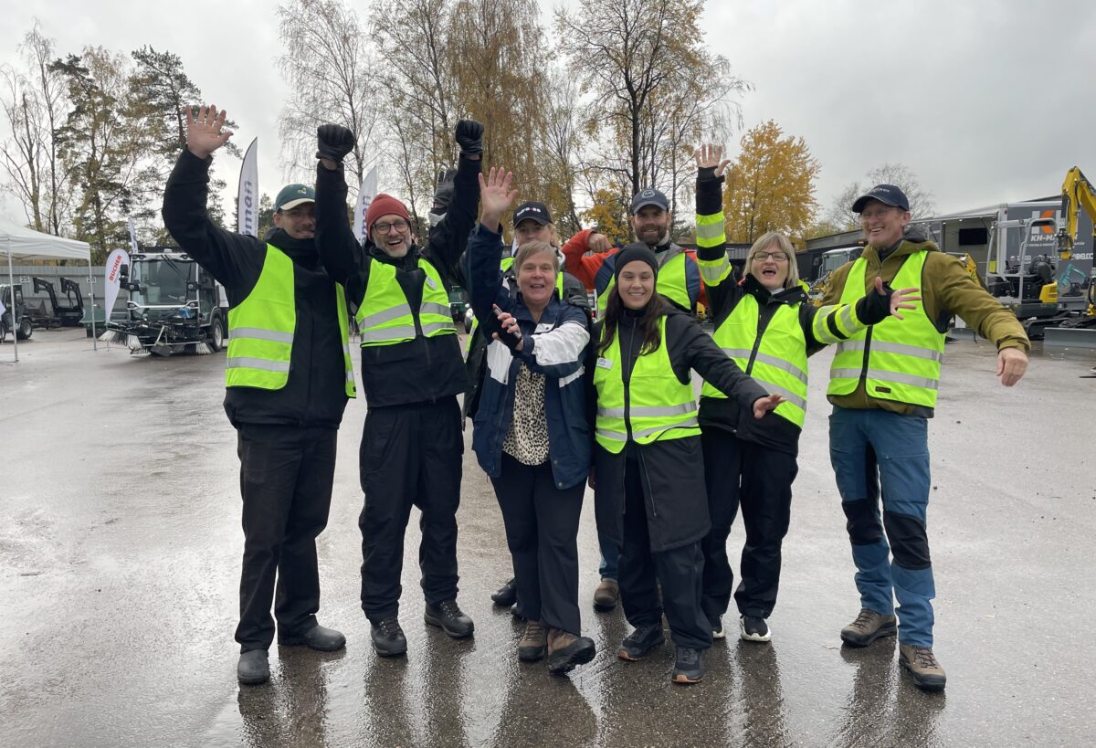 En grupp människor med signaljackor gör segergester och skrattar. I Bakgrunden flera arbetsmaskiner.