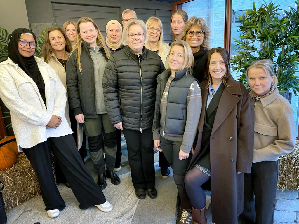 En stor grupp kvinnor med ytterkläder tittar in i kameran.