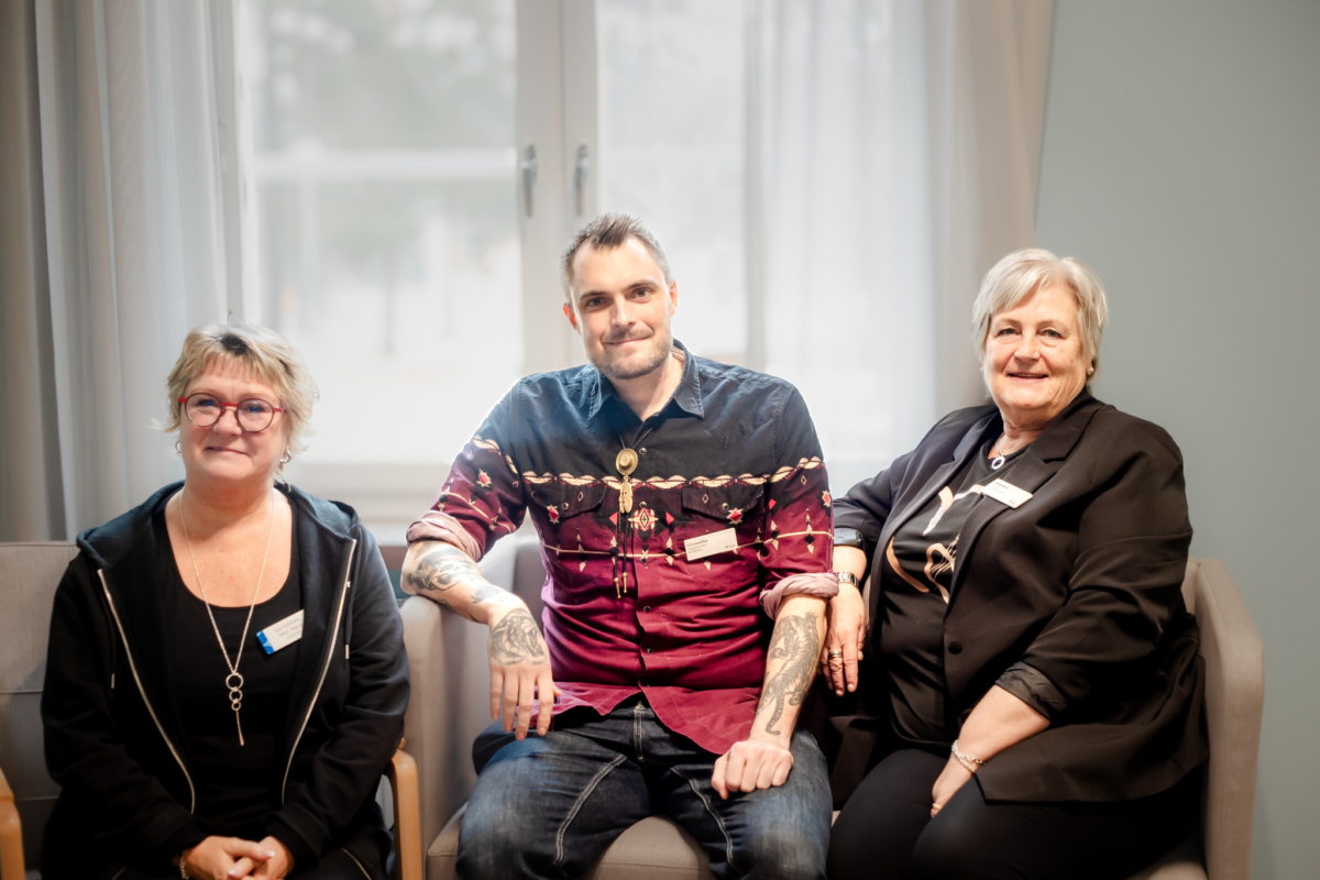Tre personer sitter på stolar och tittar in i kameran.