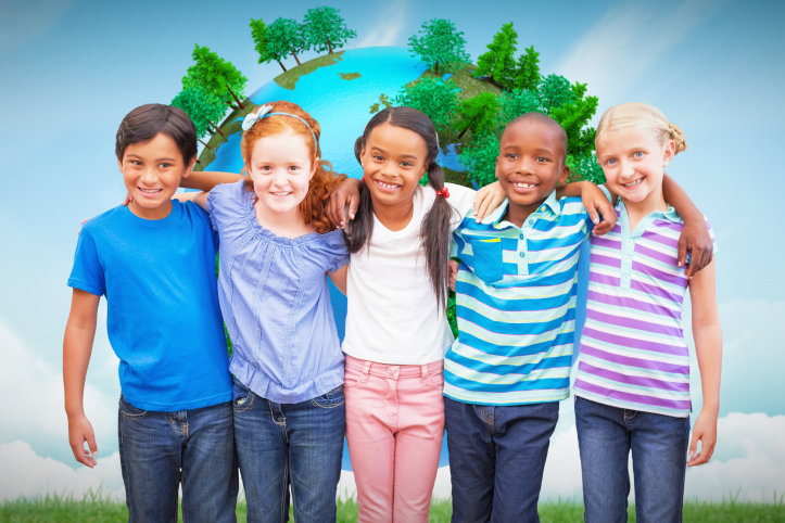 Cute pupils smiling at camera in classroom against blue sky over green field